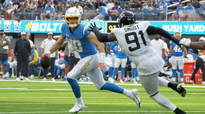 Sep 25, 2022; Inglewood, California, USA; Los Angeles Chargers quarterback Justin Herbert (10) runs the ball under pressure from Jacksonville Jaguars defensive end Dawuane Smoot (91) in the third quarter at SoFi Stadium.